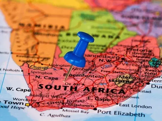 A blue thumb tack pushed into a map of South Africa