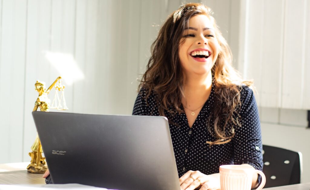 A woman smiling while using a laptop