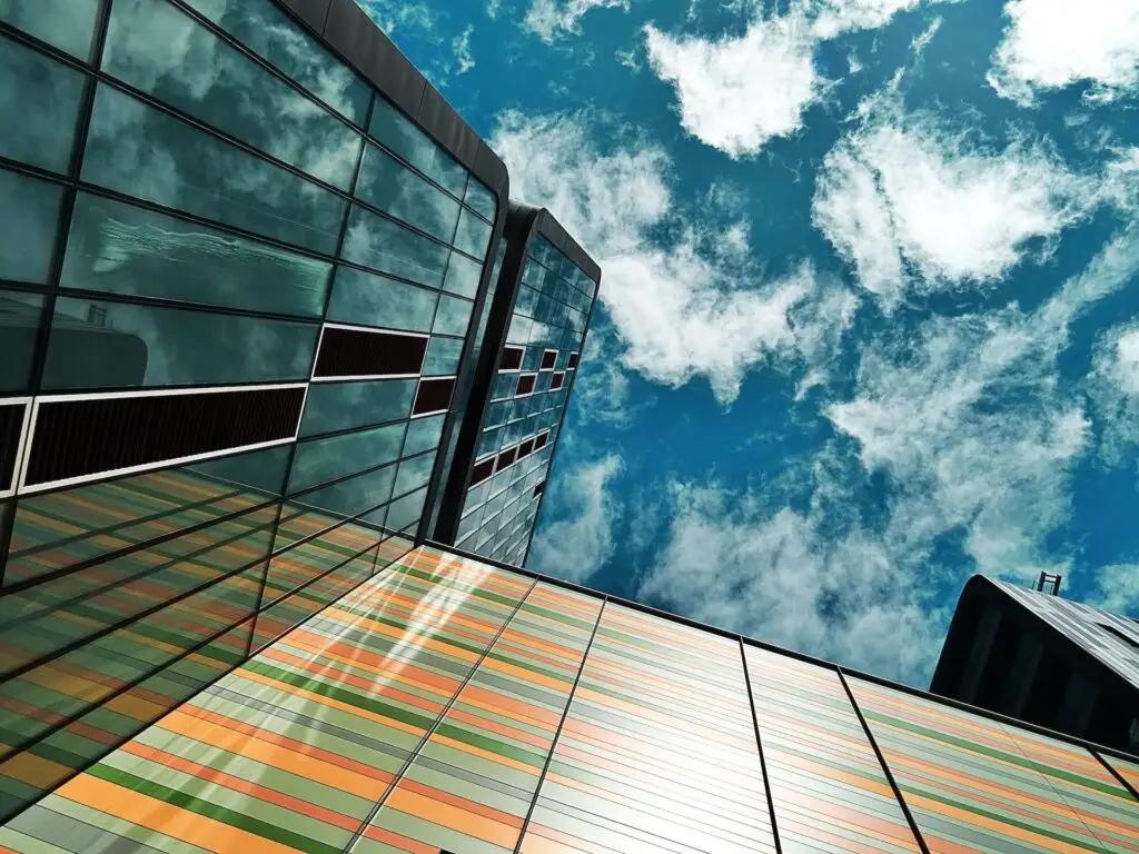 A view of looking up a building with blue sky and clouds