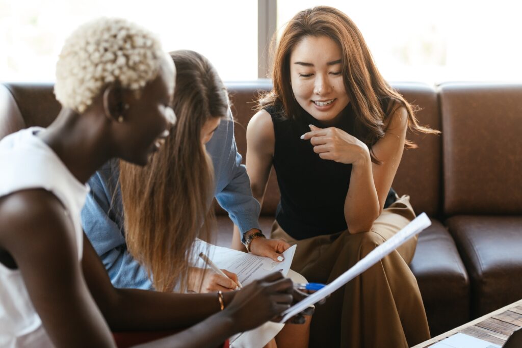 A group of women reviewing paperwork on a sofa