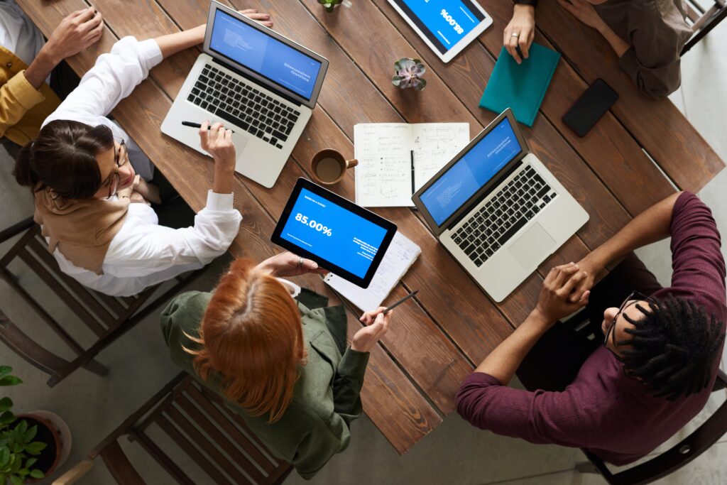 A group of people sitting around a table with laptops