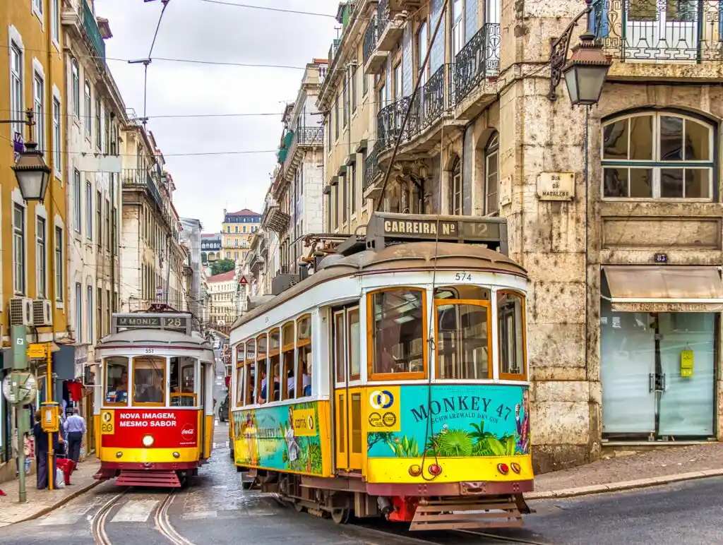 A view of two brightly coloured trams in the streets of a city in Portugal