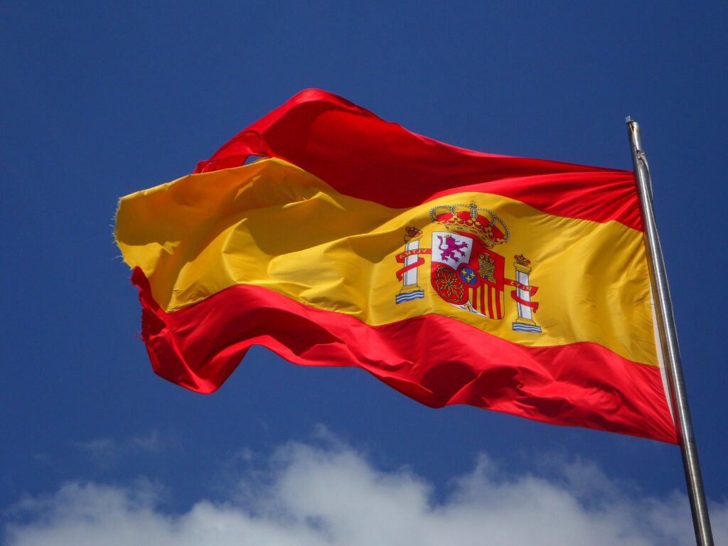 The flag of Spain (España) flying in the breeze against a bright blue sky