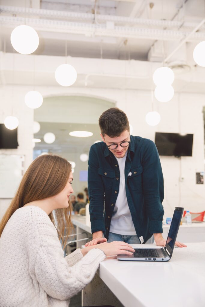 A man and woman looking at a laptop in a bright office