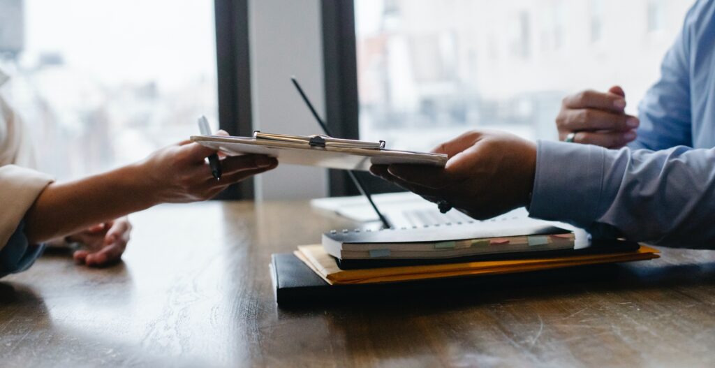 A pair of office workers passing a clipboard